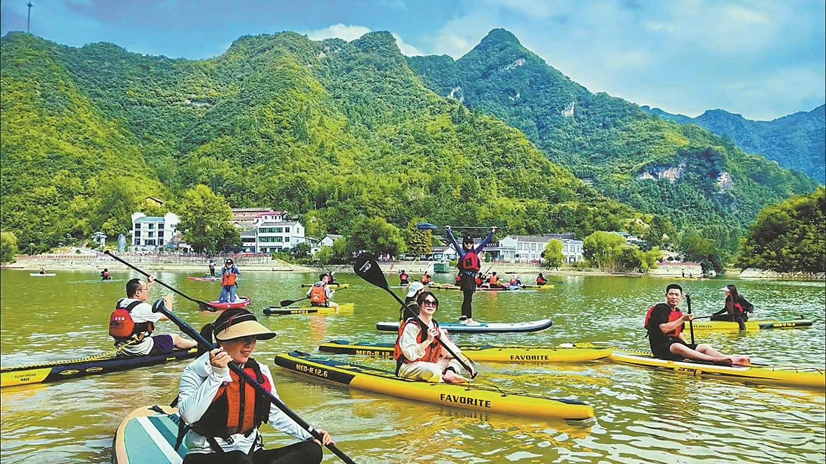 在南河小三峡景区碧波荡漾的水面上,游客手持桨板体验水上运动的乐趣。(资料图片) 记者 童光辉 通讯员 肖珩 摄